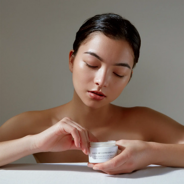 coréenne française visage fille peau blanche tient dans ses mains crème hydratante visage bouclier urbain days of confidence marque de beauté et bien etre holistique 