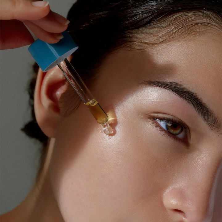 joue visage jeune fille naturelle qui applique une goutte de l’huile visage apaisante marque beauté bien être holistique days of confidence à l’aide d’une pipette bleue 